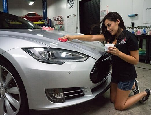 A lady waxing a white vehicle with the best car wax for white cars
